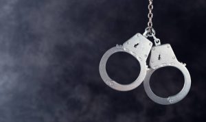Handcuffs hanging against a dark background with copy space
